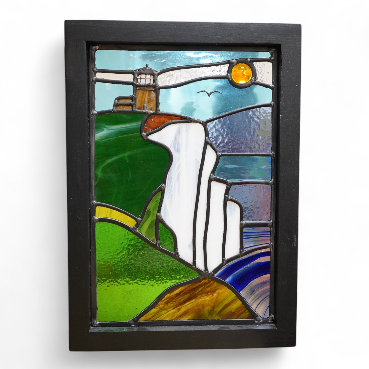 A contemporary leaded stained glass panel, Beachy Head lighthouse, framed, 51cm high overall